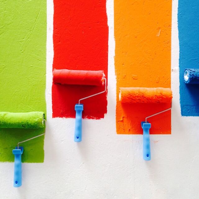 Top down view of three paint buckets with grey red and blue paint in them